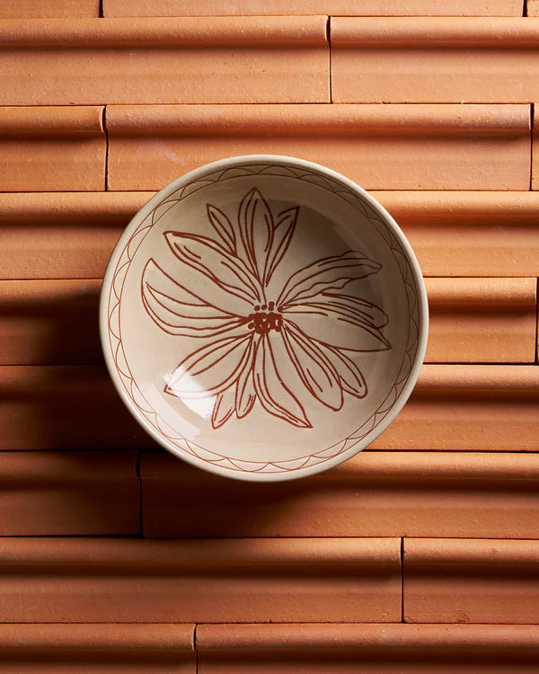 Ceramic bowl with floral design on a terracotta surface