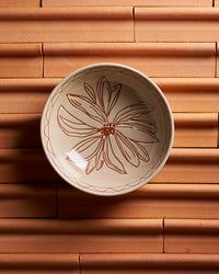 Ceramic bowl with floral design on a terracotta surface
