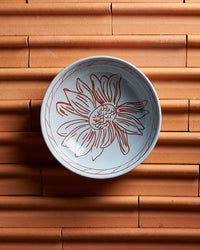 Ceramic bowl with floral design on a terracotta surface