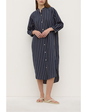 Person wearing a navy and white striped dress against a white background