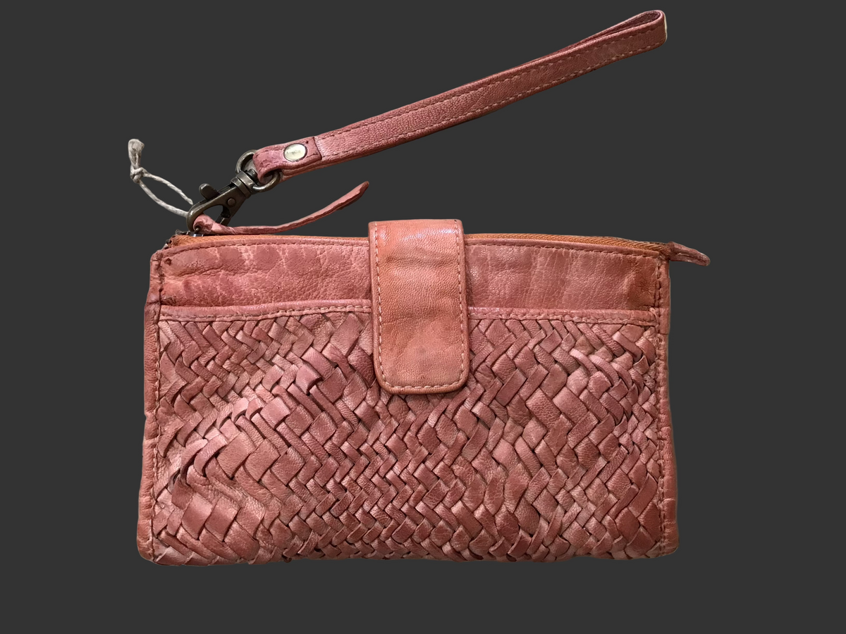 Tan woven clutch bag on a wooden surface