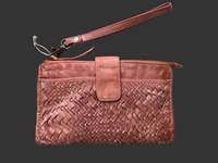 Tan woven clutch bag on a wooden surface