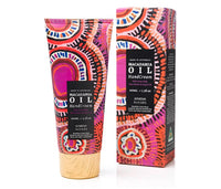 A squeeze tube and matching box of Macadamia Oil Hand Cream, both decorated with a vibrant pink, orange, and black circular pattern, with a light wood-toned cap on the tube, set against a plain white background.