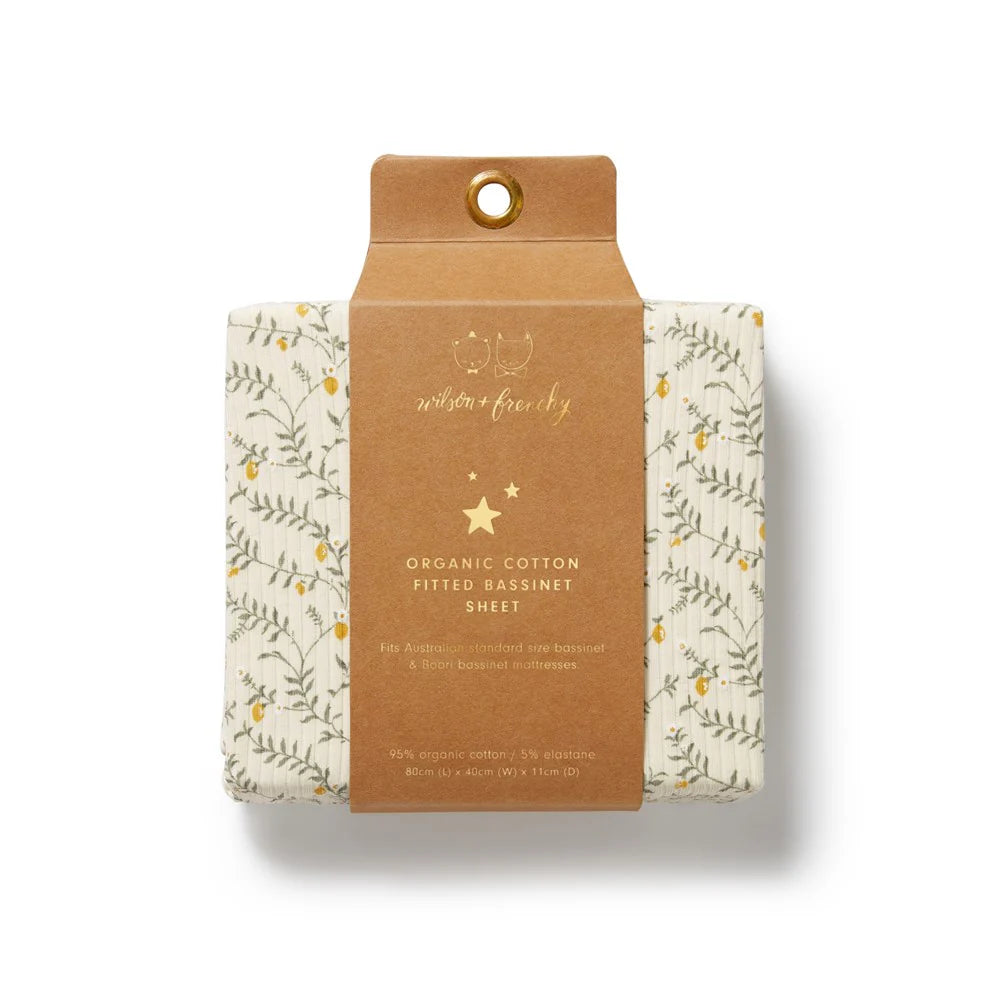 Packaged organic cotton fitted bassinet sheet with floral design on a beige background