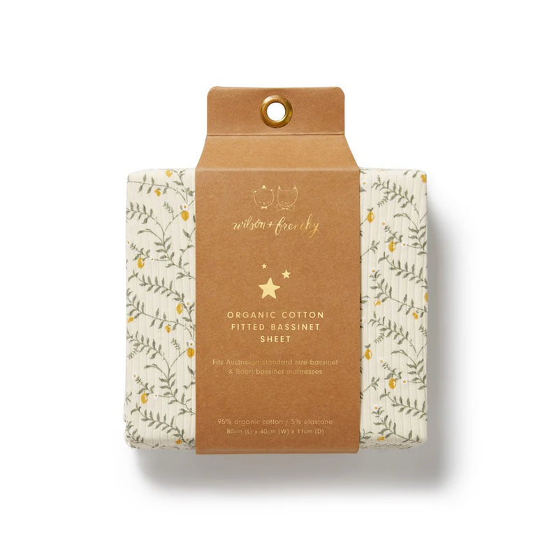 Packaged organic cotton fitted bassinet sheet with floral design on a beige background