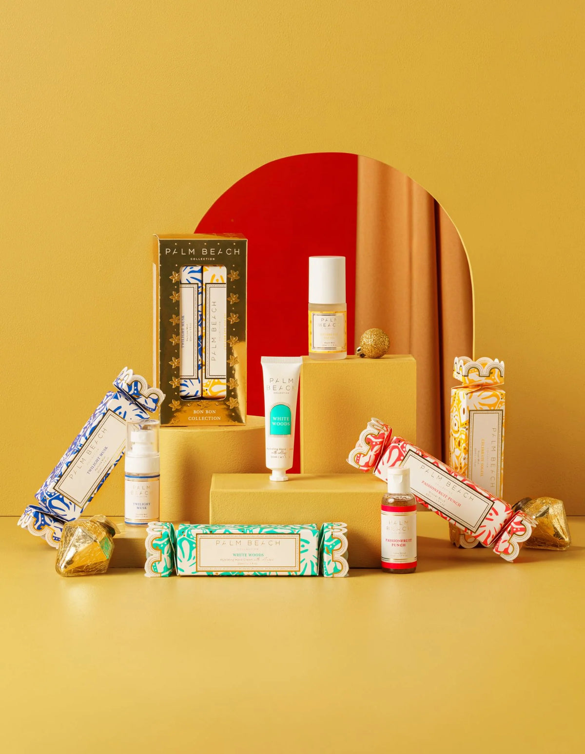 Collection of beauty products on a yellow surface with a red mirror in the background